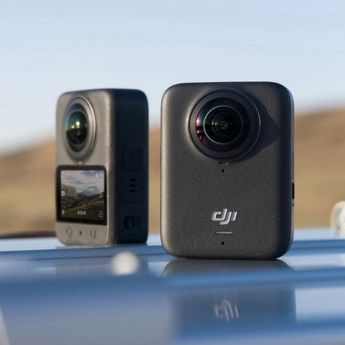 DJI Osmo 360 Action Camera - Two DJI action cameras on a reflective surface with a blurred natural background