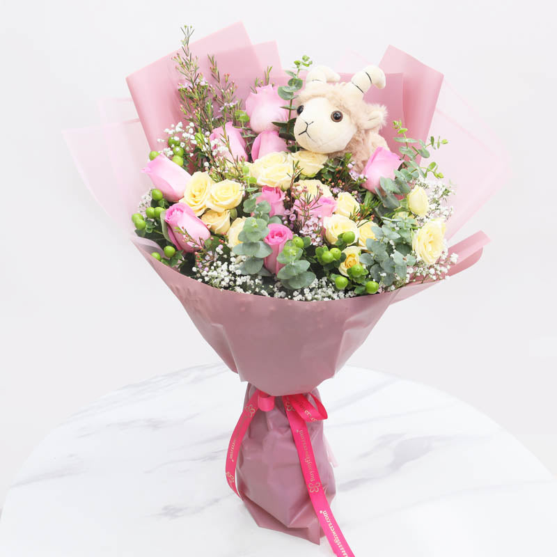 Blessing of AdhaFlowers1 Sheep Plush Toy 20cm, 10 Pink Roses, 5 Stems Peach Baby Roses, 3 Green Hypericum, 1 Stem Pink Wax Flower, Leaves - 2 Stem Eucalyptus, Fillers - 1 Stem Baby Breath, Wrapped In Purple And Pink Paper, Tied With Dark Pink Ribbon.