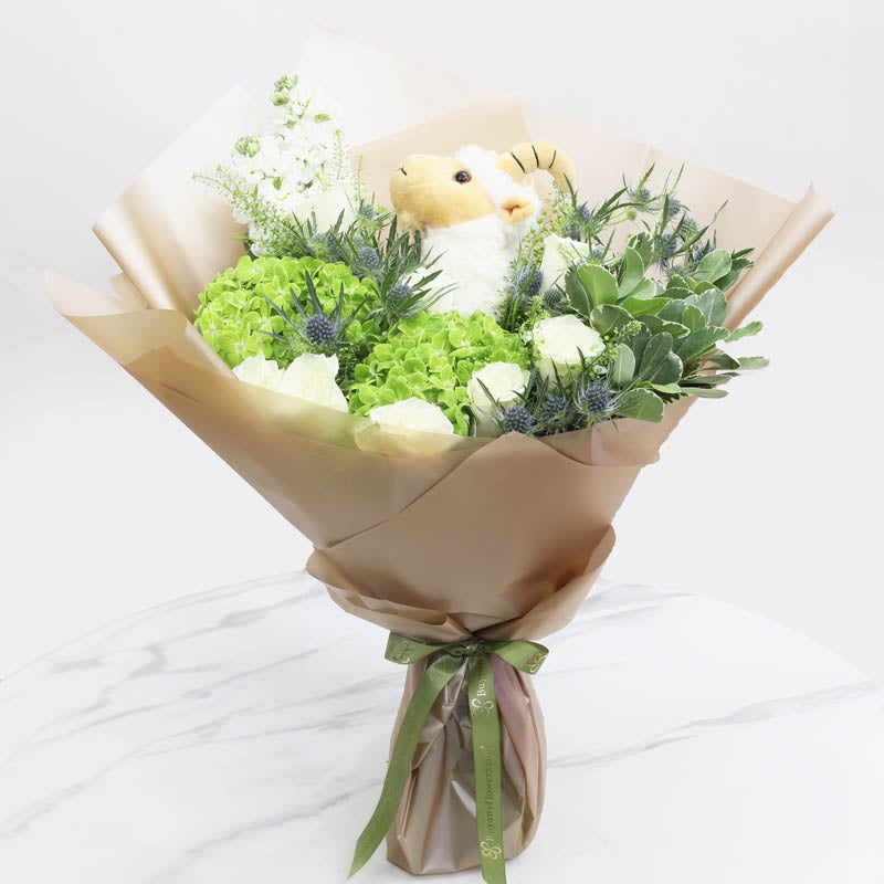Ghanmat Al-NadaFlowers1 Sheep Plush Toy 20cm, 2 Green Hydrangea, 10 White Roses, 1 White Mathiola, 4 Stems Blue Eryngiums, Leaves - 2 Stems Pittosporum, Fillers - 2 Stems Lipidium, Wrapped In Beige Wrapping, Tied with Green Ribbon.