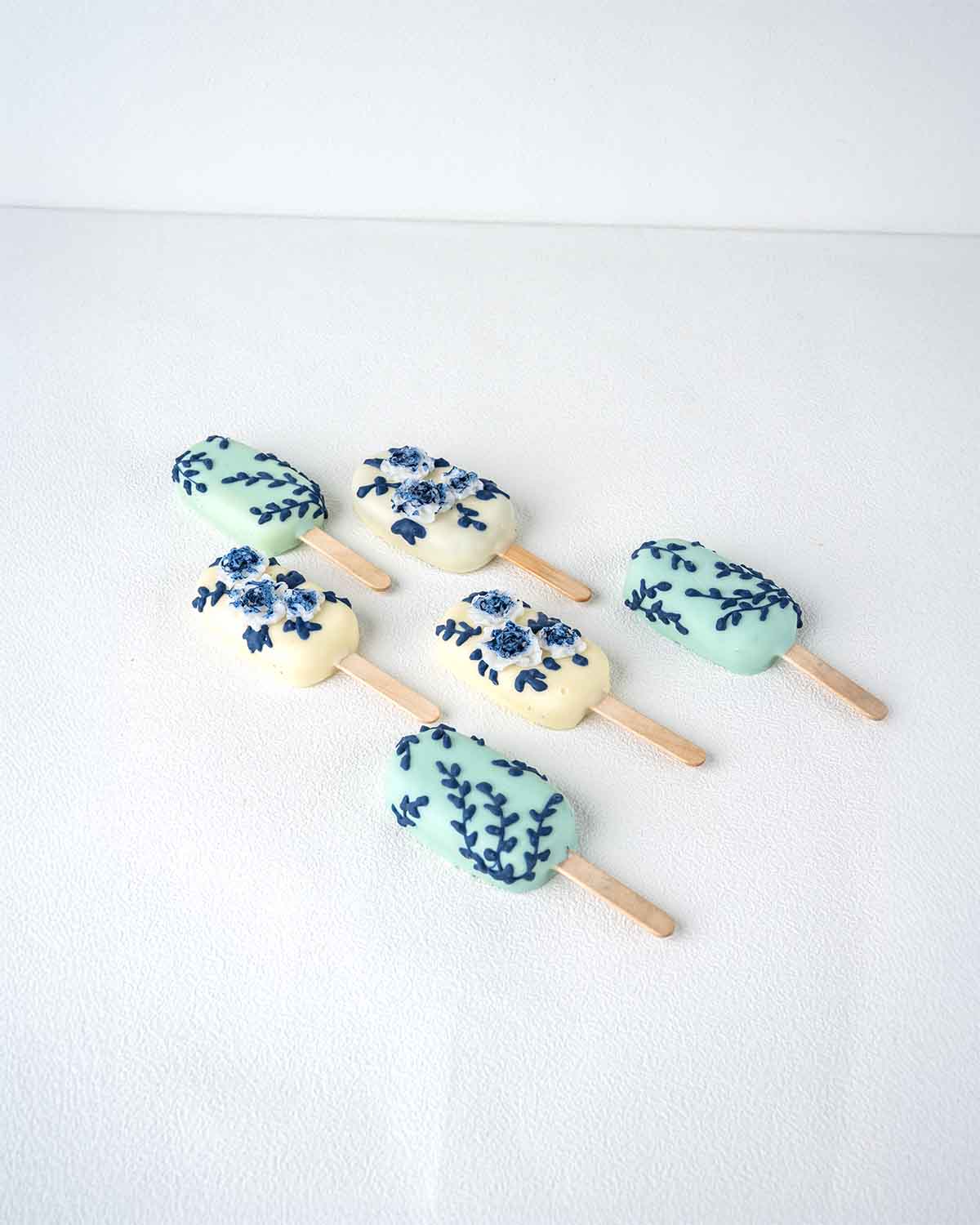 White and Blue CakesiclesChocolate & ConfectioneryWhite and Blue Cakesicles – A Sophisticated Sweet for Any Celebration Add a touch of elegance to your celebration with these beautifully designed white and blue cakesicles. Dipped in smooth chocolate and d