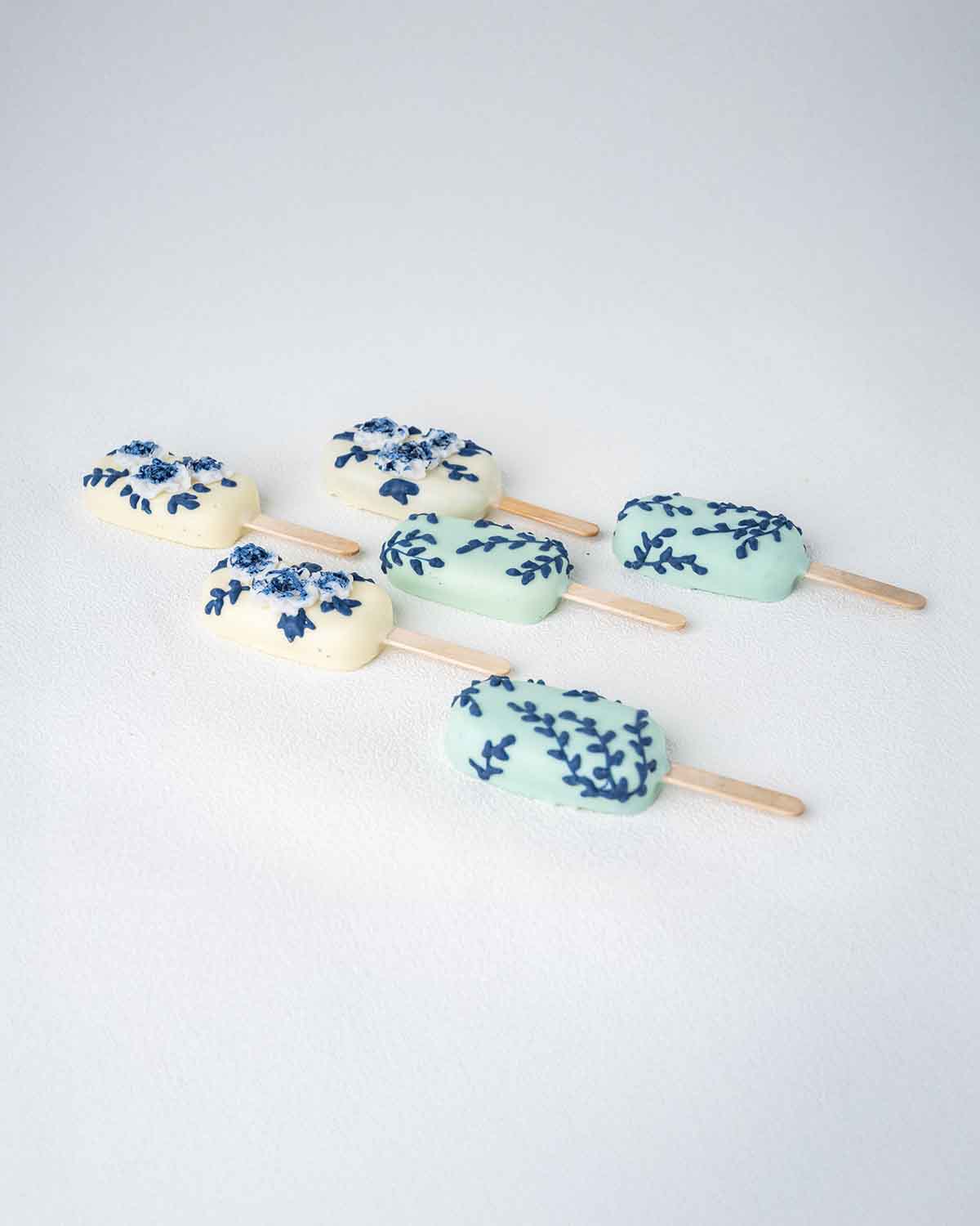 White and Blue CakesiclesChocolate & ConfectioneryWhite and Blue Cakesicles – A Sophisticated Sweet for Any Celebration Add a touch of elegance to your celebration with these beautifully designed white and blue cakesicles. Dipped in smooth chocolate and d
