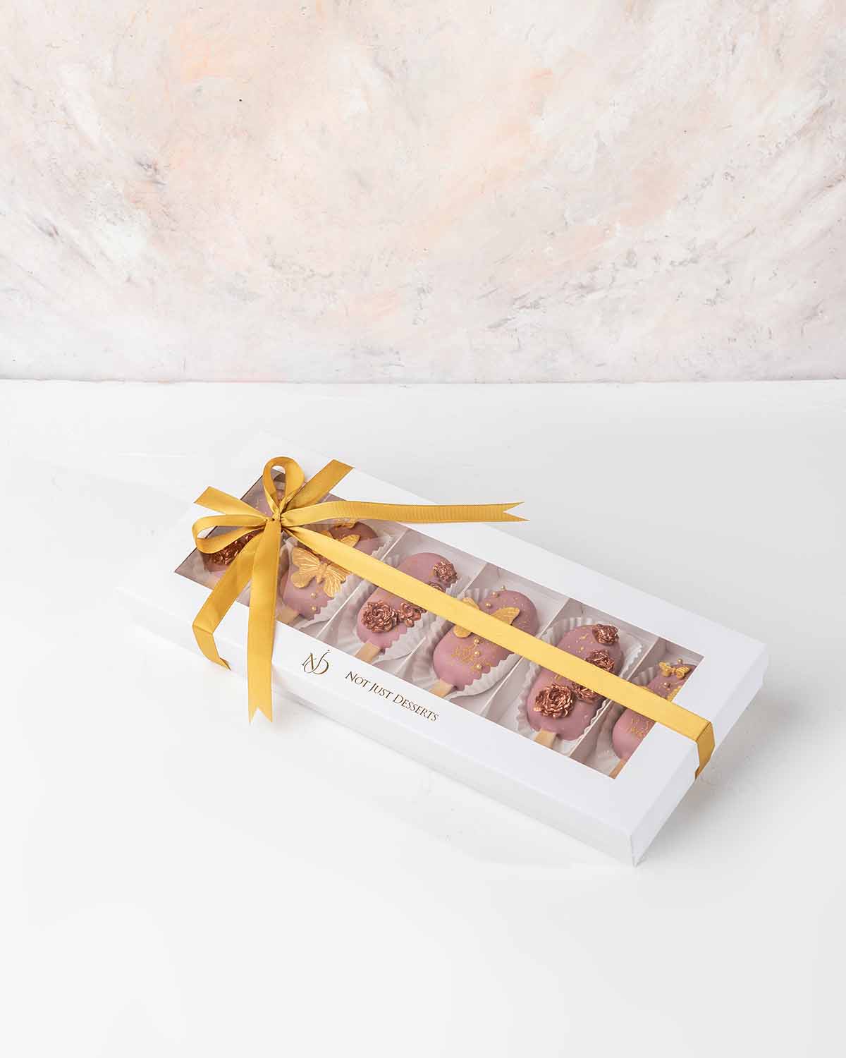 Women's Day Cakesicles by NJDChocolate & ConfectioneryYour Gift Contains:• 6 Women's Day theme Cakesicles • Flavors available: Chocolate/Vanilla/Red Velvet• Box Size: 35x15x4cmHandling and Storage • Keep away from direct heat and sunlight• Best stored bet