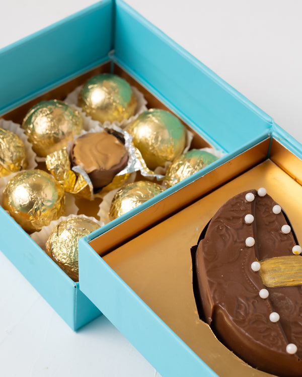 Diya and Golden Truffles by NJDChocolate & ConfectioneryYour Gift Contains: • 1 Milk chocolate Diya Bar • 9 assorted Milk chocolate Truffles • Weigh of chocolate: 250grams approx. • Flavors: Pistachio, Hazelnut, Speculoos, Peanut Butter and Roche • Box Si