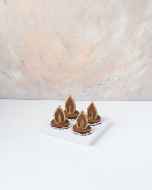 Diya Cake bitesChocolate & ConfectioneryYour Gift Contains: • 4 Milk Chocolate Diya with layers of chocolate cake and ganache • Weight of Chocolate: approx. 350grams • Box Size: 18x18x14cm Handling and Storage • Keep away from direct heat and sunlight • B