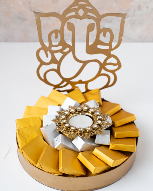 Ganesha Hamper with DiyaChocolate & ConfectioneryYour Gift Contains: • 1 designer Diya • 25 assorted Milk Chocolate • Weigh of chocolate: 400grams • Flavors: Pistachio, Hazelnut, Speculoos, Peanut Butter and Roche • Tray dimensions: 20x23cm • Design of Di