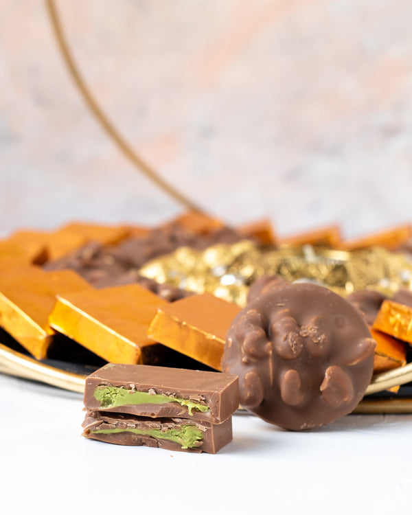 Golden and Orange HamperChocolate & ConfectioneryYour Gift Contains: • 1 designer Diya • 27 assorted Milk chocolates • 19 roasted nuts base Milk chocolate coins • 100gms of Wheat Crispies Dragee • Weigh of chocolate: 850gms approx. • Flavors: Pistachio, H