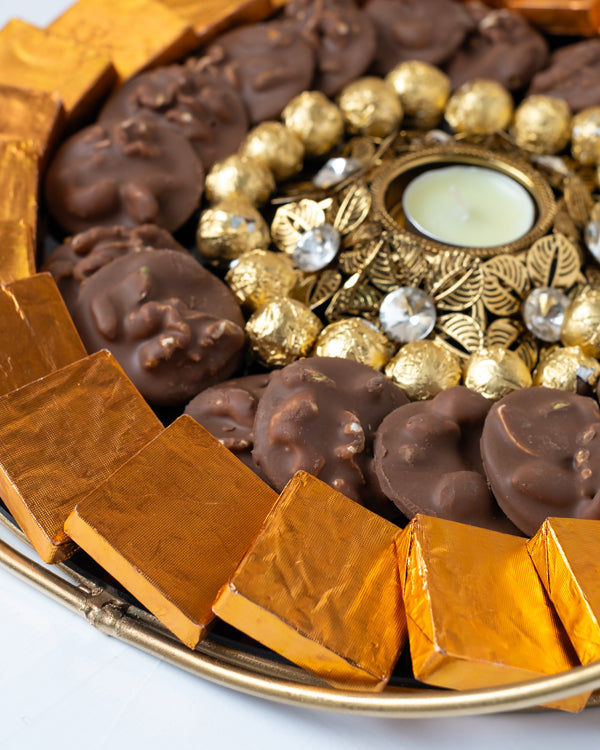 Golden and Orange HamperChocolate & ConfectioneryYour Gift Contains: • 1 designer Diya • 27 assorted Milk chocolates • 19 roasted nuts base Milk chocolate coins • 100gms of Wheat Crispies Dragee • Weigh of chocolate: 850gms approx. • Flavors: Pistachio, H