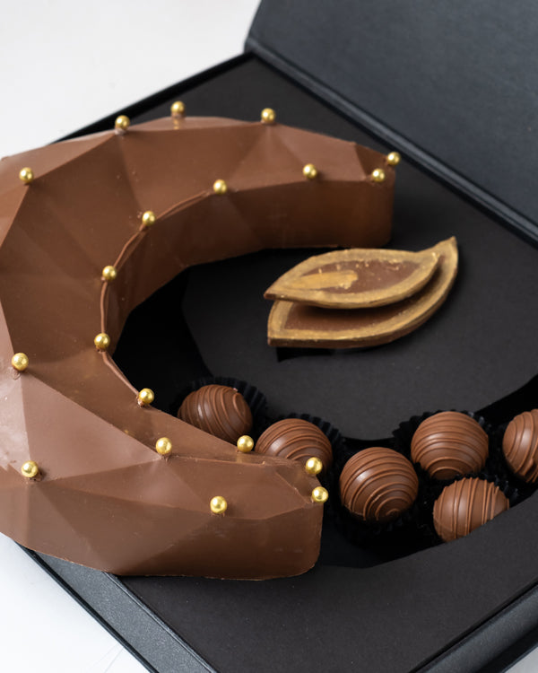 Smashable Pinata Diya by NJDChocolate & ConfectioneryYour Gift Contains: • 300gms Milk chocolate Crescent • 15 milk chocolate truffles in assorted flavors: Pistachio, Peanut Butter, Lotus and Roche • Hammer x 1 • Chocolate size: 19x23x5.5cm • Box Size: 32