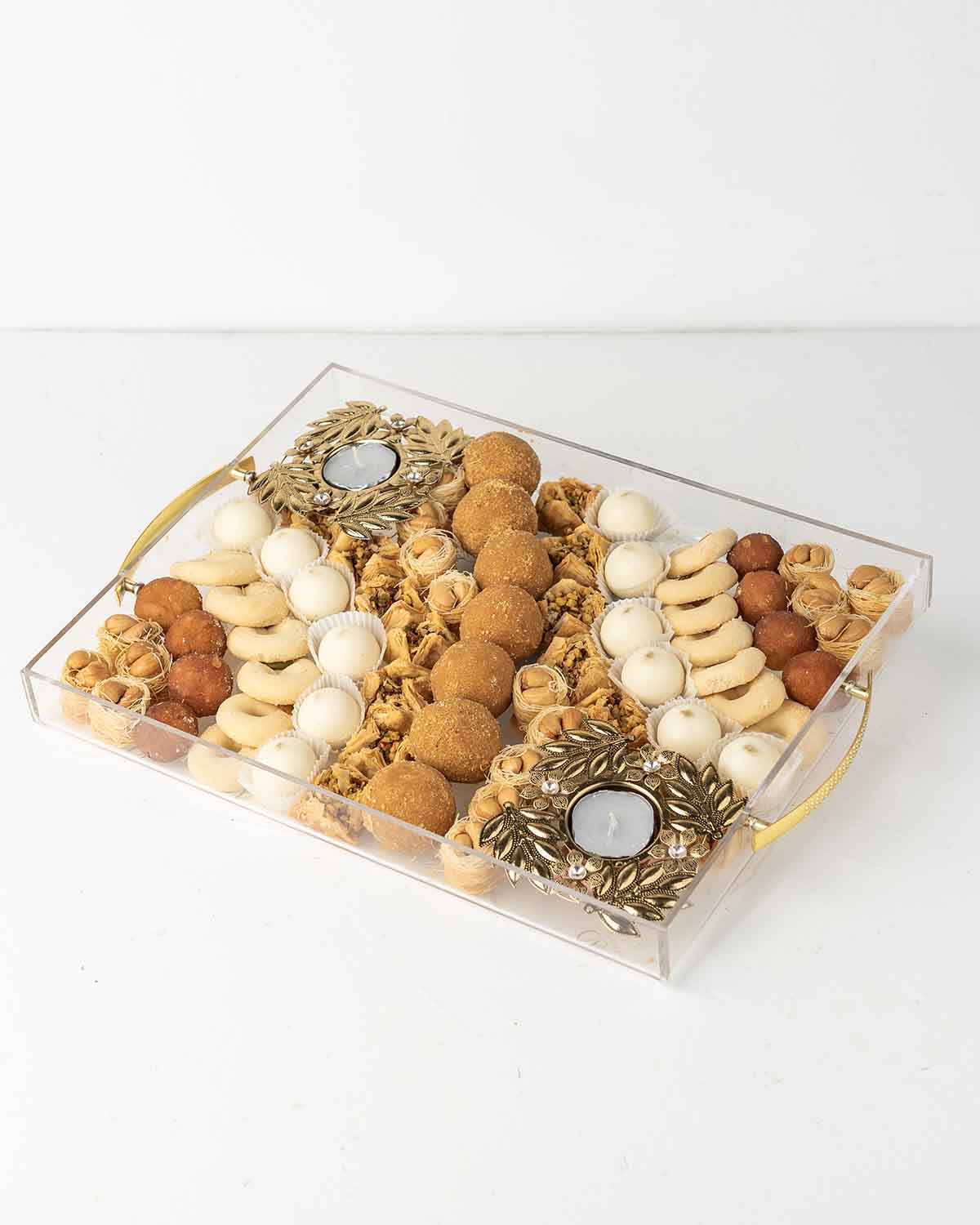 Diwali'24 Tray GiftChocolate & ConfectioneryYour Gift Contains:• 2 x designer metal Diya• 18 x Esch Cashew• 8 x Gulab Jamun• 7 x Besan Laddu • 13 x Ghraieb• 15 x Bookaj Pistachio• 12 x White chocolate assorted truffles filled in Pistachio, Kunafa, Hazelnu