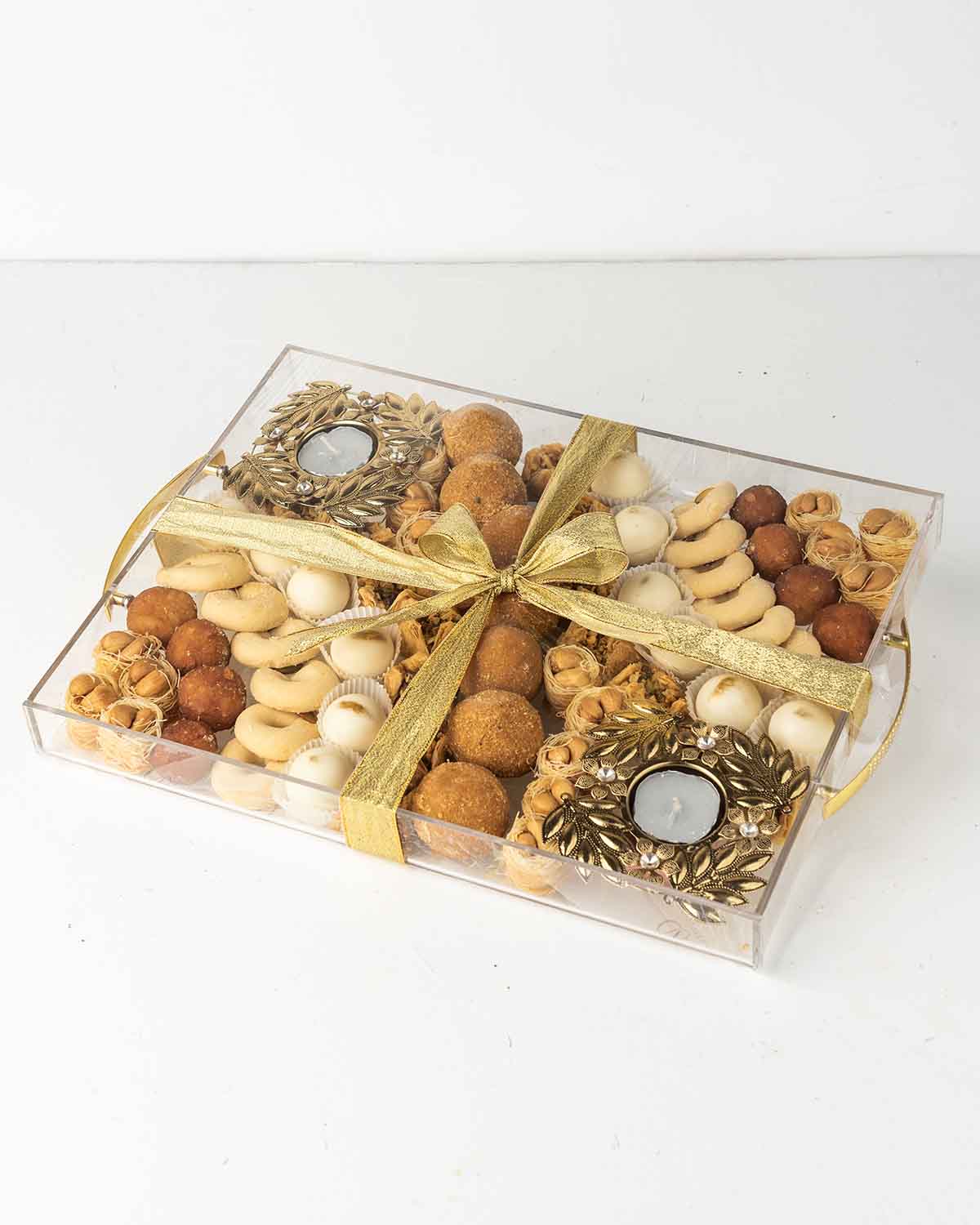 Diwali'24 Tray GiftChocolate & ConfectioneryYour Gift Contains:• 2 x designer metal Diya• 18 x Esch Cashew• 8 x Gulab Jamun• 7 x Besan Laddu • 13 x Ghraieb• 15 x Bookaj Pistachio• 12 x White chocolate assorted truffles filled in Pistachio, Kunafa, Hazelnu