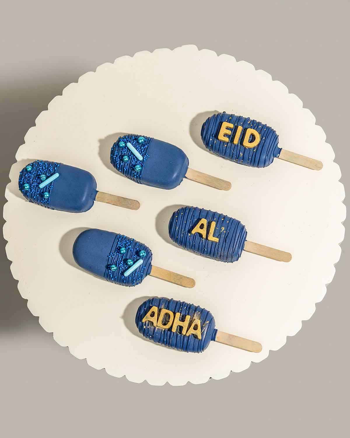 Designer Blue CakesiclesChocolate & ConfectioneryYour Gift Contains:• 6pcs Eid al adha Theme Cakesicles• Flavors available: Chocolate/Vanilla/Red Velvet• Chocolate Weight: 350g• Box Size: 35x14.5x4cmHandling and Storage • Keep away from direct heat and su