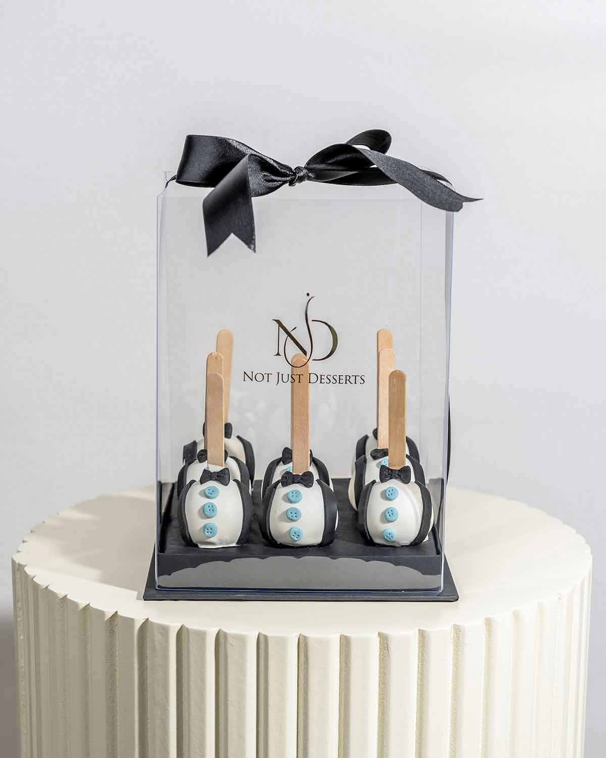 Cake Pops with Bow TieChocolate & ConfectioneryYour Gift Contains:• 9 x Father's Day theme cake pops• Flavors available: Chocolate/Vanilla/Red Velvet• Chocolate Weight: 450gms approx. • Box Size: 16x16x20cmHandling and Storage • Keep away from direct heat