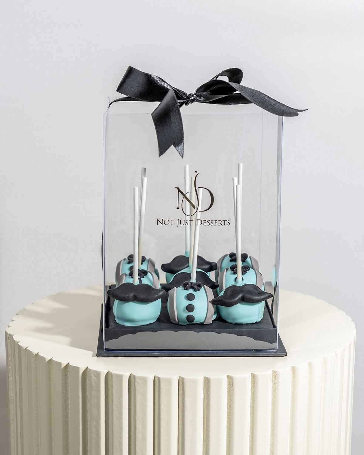 Cake Pops with MoustacheChocolate & ConfectioneryYour Gift Contains:• 9 x Father's Day theme cake pops• Flavors available: Chocolate/Vanilla/Red Velvet• Chocolate Weight: 450gms approx. • Box Size: 16x16x20cmHandling and Storage • Keep away from direct he