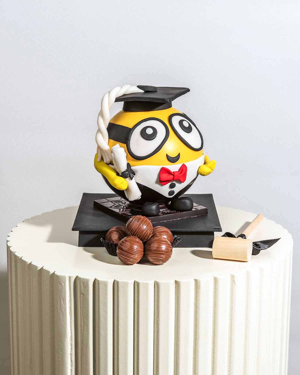 Graduation Theme Minion by NJDChocolate & ConfectioneryYour Gift Contains:• 1 x Graduation Minion theme smashable ball • 10 assorted Milk Chocolate Truffles • Total weight of the chocolate: 575g• Flavors: Pistachio, Hazelnut, Speculoos, Peanut Butter and