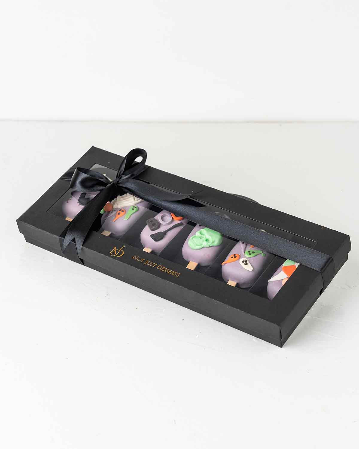 Purple Spooky CakesiclesChocolate & ConfectioneryYour Gift Contains:• 6 Halloween theme Cakesicles• Flavor: Chocolate/Vanilla/Red Velvet• Box Size: 35×14.5x4cmHandling and Storage • Keep away from direct heat and sunlight• Best stored between 12-18 °C• No