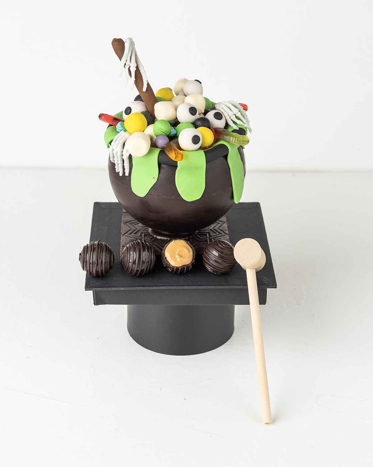Smashable CauldronChocolate & ConfectioneryYour Gift Contains:• 3D Halloween Smash Ball • 10 Pcs Dark Chocolate Truffles filled in Pistachio, Hazelnut, Speculoos, Peanut Butter and Roche• 1x Hammer• Weight of Chocolate: 755g• Chocolate Size: 13x13x18cm• B