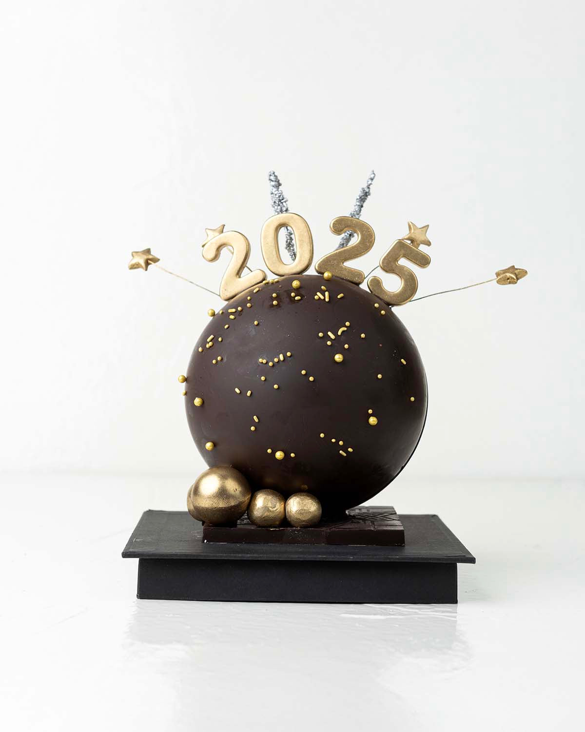 2025 Smash BallChocolate & ConfectioneryYour Gift Contains:• 2025 Theme Dark Chocolate Smash Ball• 11 x Milk Chocolate Assorted Truffles• Flavors: Pistachio, Hazelnut, Speculoos, Peanut Butter and Roche • Chocolate size: 12x12x18cm• 1x Hammer• Chocolate W