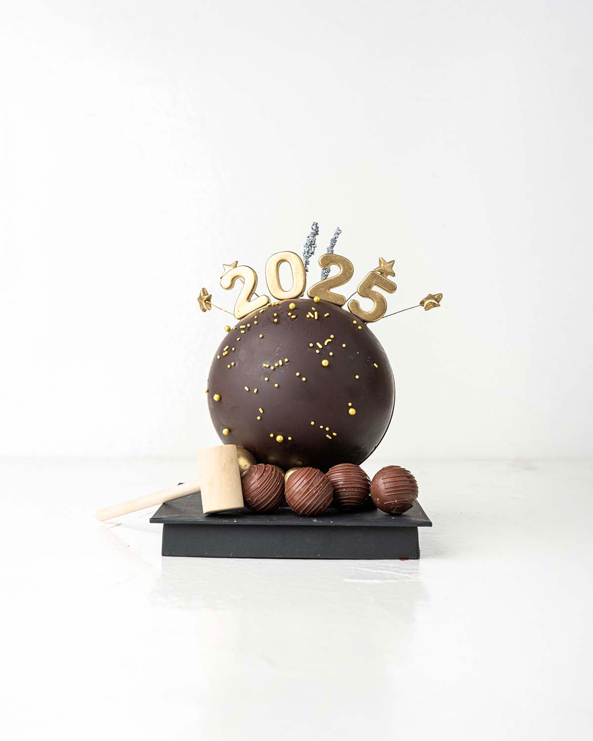 2025 Smash BallChocolate & ConfectioneryYour Gift Contains:• 2025 Theme Dark Chocolate Smash Ball• 11 x Milk Chocolate Assorted Truffles• Flavors: Pistachio, Hazelnut, Speculoos, Peanut Butter and Roche • Chocolate size: 12x12x18cm• 1x Hammer• Chocolate W