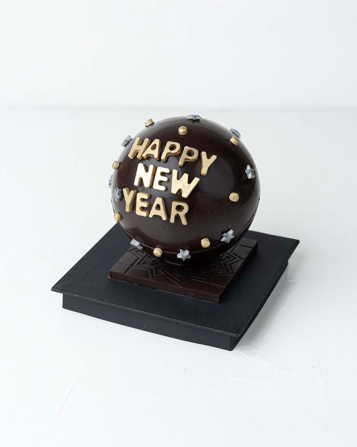 Happy New Year Smash BallChocolate & ConfectioneryYour Gift Contains:• 500grams Dark Chocolate Smash Ball• 11 x Milk Chocolate Assorted Truffles• Flavors: Pistachio, Hazelnut, Speculoos, Peanut Butter and Roche • Chocolate size: 12x12x18cm• 1x Hammer• Box
