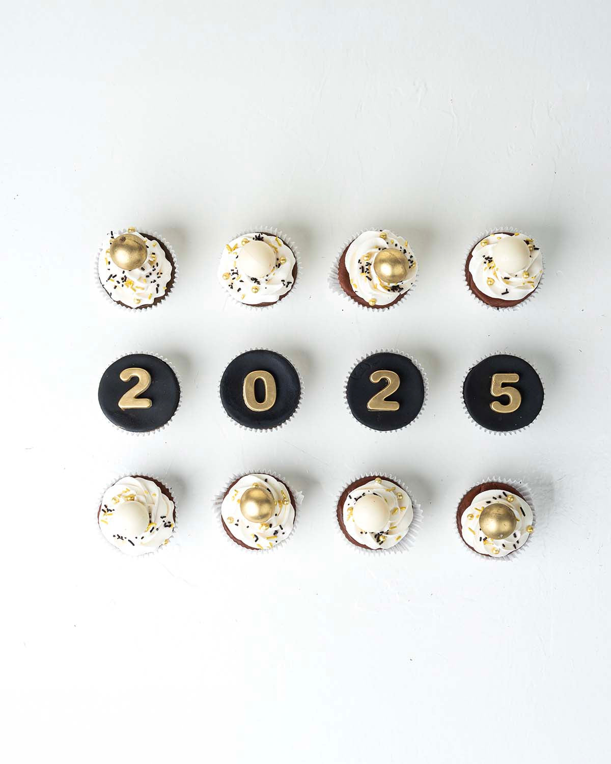 12 New Year Theme CupcakesChocolate & ConfectioneryYour Gift Contains:• 12 Year 2025 Theme cupcakes• 8 assorted White and gold truffles• Flavors: Pistachio, Hazelnut, Speculoos, Peanut Butter and Roche• Flavor: Chocolate/Vanilla/Red Velvet• Box Size: 34 x