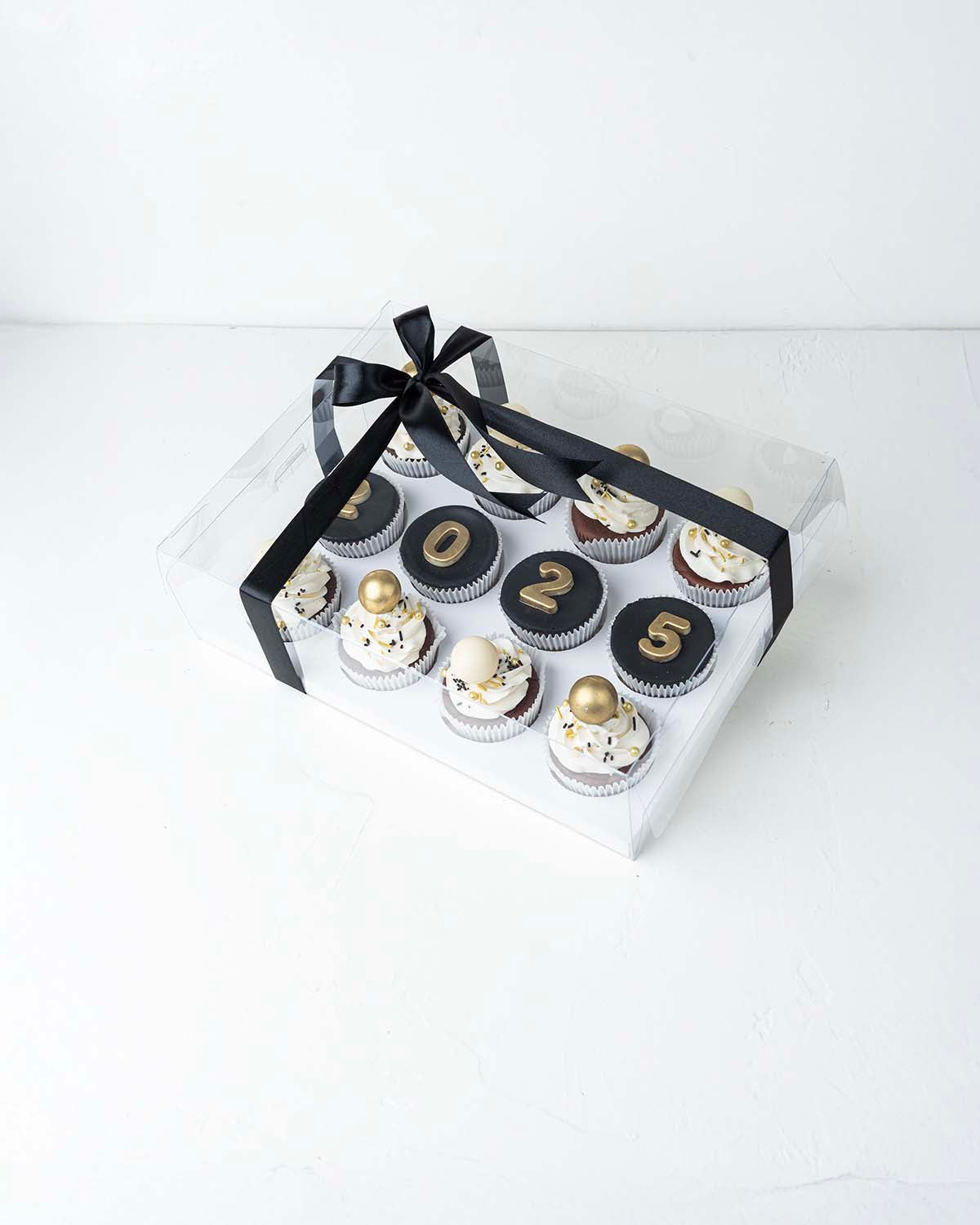 12 New Year Theme CupcakesChocolate & ConfectioneryYour Gift Contains:• 12 Year 2025 Theme cupcakes• 8 assorted White and gold truffles• Flavors: Pistachio, Hazelnut, Speculoos, Peanut Butter and Roche• Flavor: Chocolate/Vanilla/Red Velvet• Box Size: 34 x