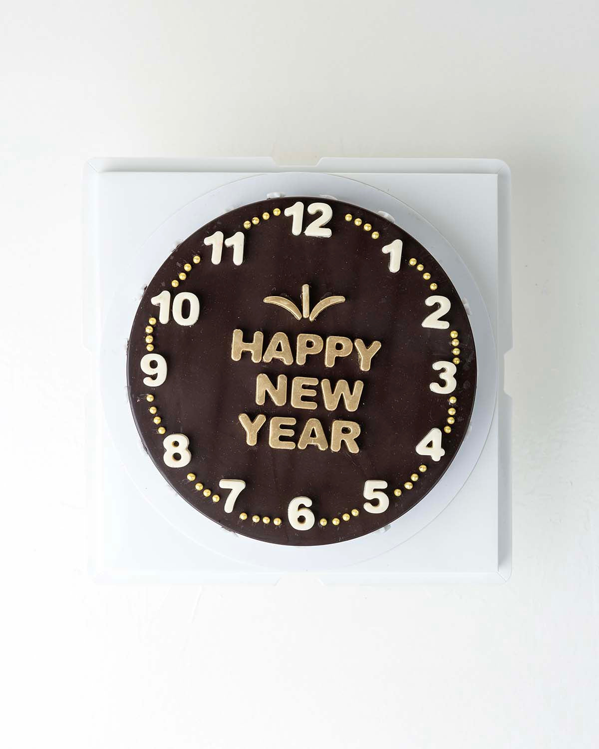 Happy New Year Cake with ChocolateChocolate & ConfectioneryYour Gift Contains:• 600grams Happy New Year Dark • 10 assorted Dark Chocolate Truffles• Flavors: Pistachio, Hazelnut, Speculoos, Peanut Butter and Roche • Chocolate size: 21x21x4cm• 1x Hammer• Bo