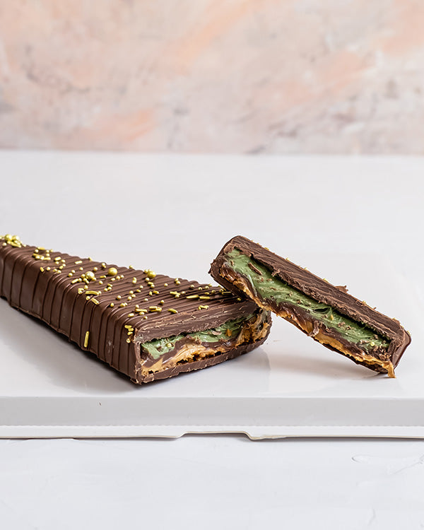 Mini Christmas treeChocolate & ConfectioneryYour Gift Contains: • Triangle shaped chocolate bar with multiple layer filling • Flavor: Pistachio, Roasted Nuts and Biscoff • Weight of Chocolate: 300grams • Box Size: 29x12x4cm Handling and Storage • Keep awa