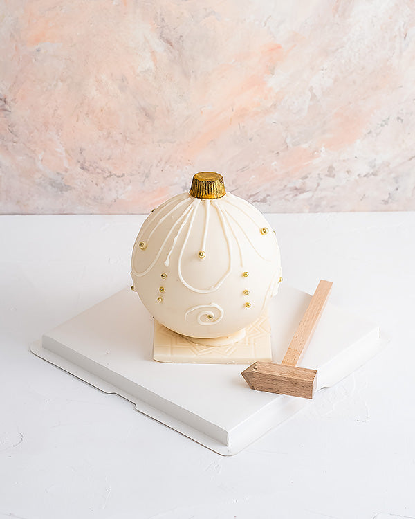 Edible Bauble by NJDChocolate & ConfectioneryYour Gift Contains: • Smash ball with 8 chunky Christmas theme assorted chocolates • Flavors: Pistachio, Sepculoos, Hazelnut, Praline, Peanut Butter • Hammer: 1 • Size of Chocolate: 12x12x14cm • Box Size: 20x20