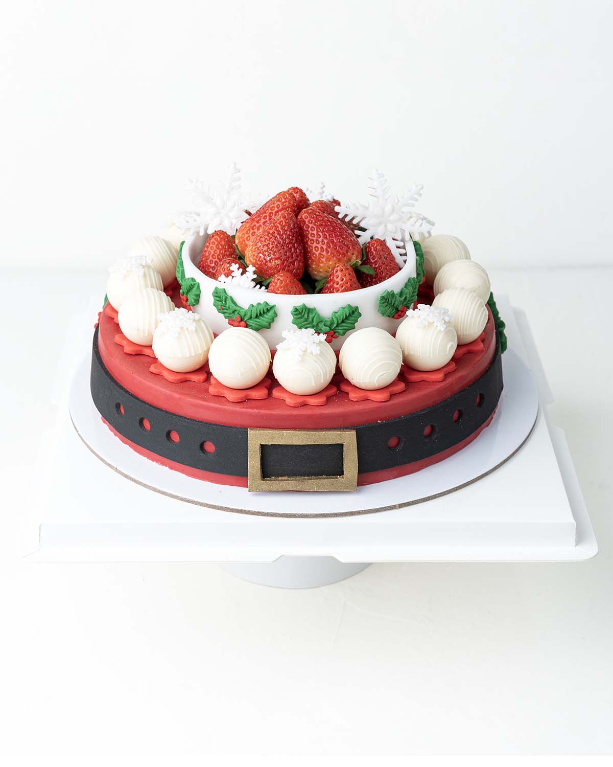 Holiday Season Cake with Fresh StrawberriesChocolate & ConfectioneryYour Gift Contains:• 1300grams Mr. Claus belt cake• 14 Fresh Strawberries • 10 assorted White Chocolate Truffles• Flavors: Pistachio, Hazelnut, Speculoos, Peanut Butter and Roche• Wooden