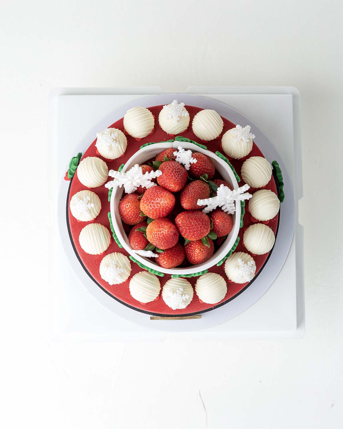 Holiday Season Cake with Fresh StrawberriesChocolate & ConfectioneryYour Gift Contains:• 1300grams Mr. Claus belt cake• 14 Fresh Strawberries • 10 assorted White Chocolate Truffles• Flavors: Pistachio, Hazelnut, Speculoos, Peanut Butter and Roche• Wooden