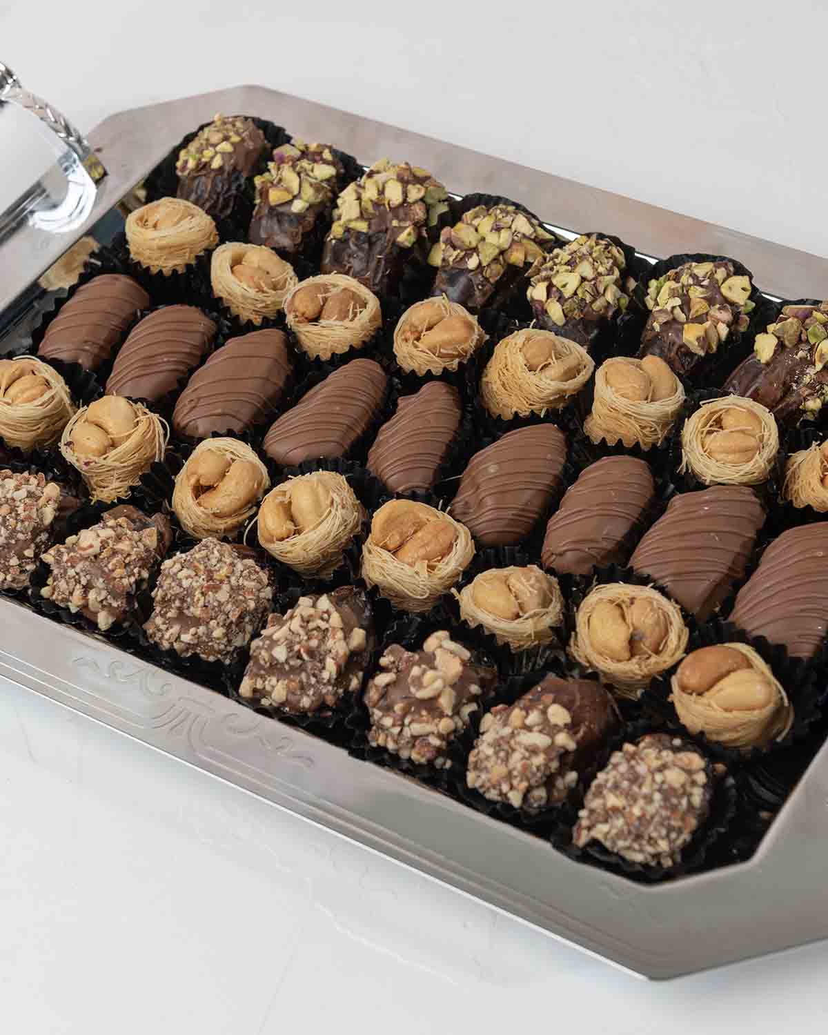 Dates and Baklawa Platter by NJDChocolate & ConfectioneryYour Gift Contains:• 8 x Chocolate Covered Roasted Pistachio Dates• 8 x Chocolate Covered Roasted Almonds Dates• 9 x Milk Chocolate Covered Dates • 16 x Bul Bul Cashew Baklawa Handling and Storage •