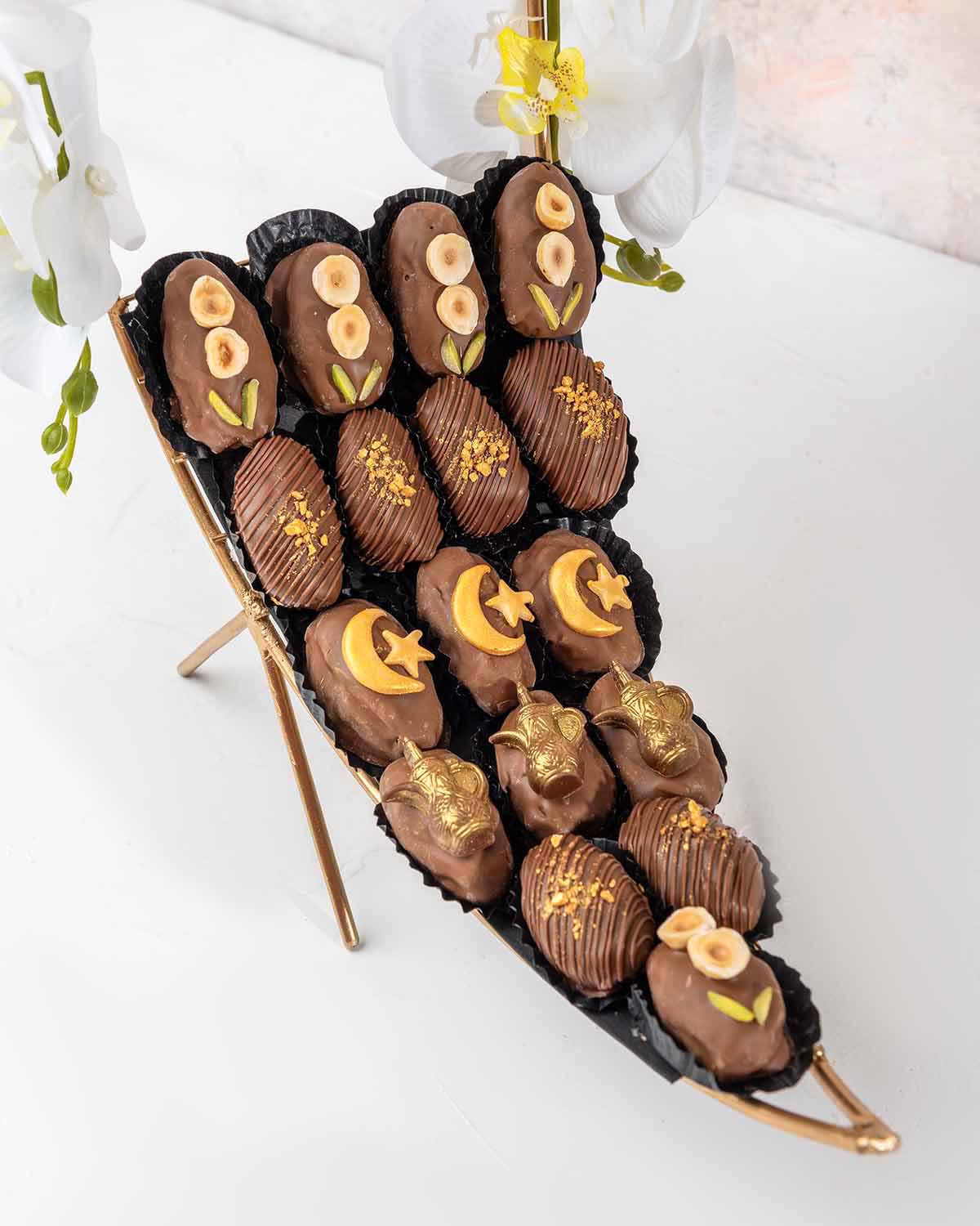 Crescent Dates Collection by NJDChocolate & ConfectioneryYour Gift Contains:• 17 x Hand designed Milk Chocolate covered dates with assorted nuts• Artificial flower arrangement• Tray Size: 30x16x36cmHandling and Storage • Keep away from direct heat and sun