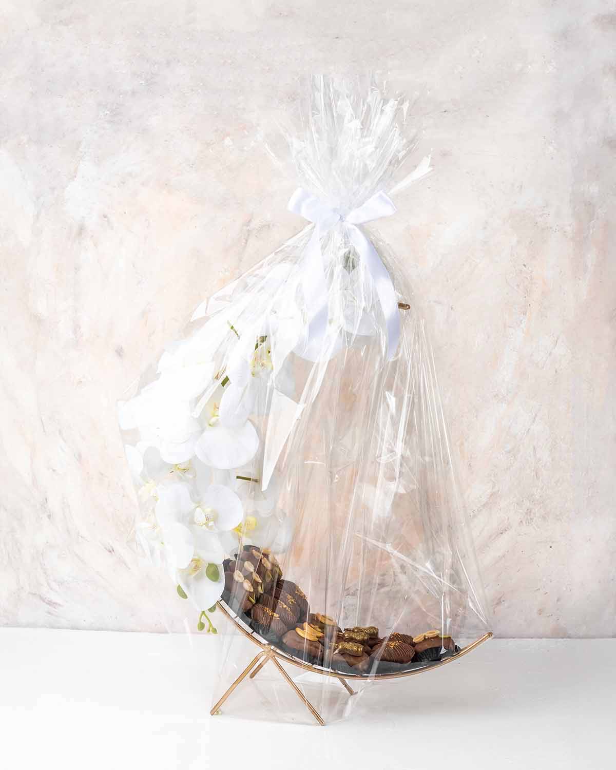 Crescent Dates Collection by NJDChocolate & ConfectioneryYour Gift Contains:• 17 x Hand designed Milk Chocolate covered dates with assorted nuts• Artificial flower arrangement• Tray Size: 30x16x36cmHandling and Storage • Keep away from direct heat and sun