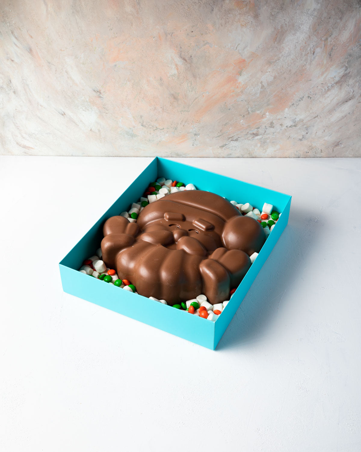 Santa in a Box by NJDChocolate & ConfectioneryYOUR GIFT CONTAINS Approx 1kg milk chocolate, mini marshmallows,orange and green candies Chocolate Dimensions: LxBxH: 25x25x5.5cm Flavors: Pure Belgian Milk chocolate and Color chocolate Box dimensions: LxBxH: