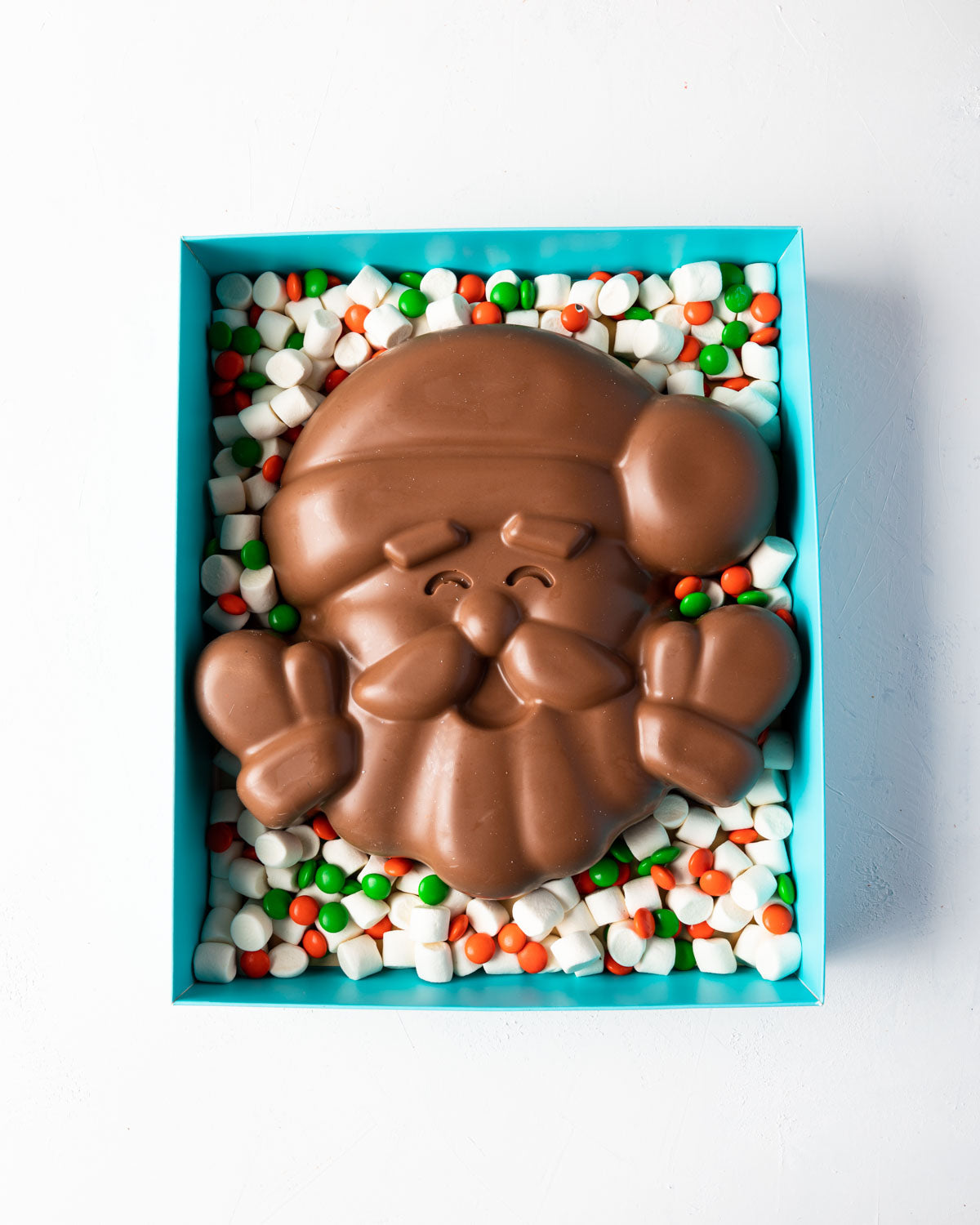 Santa in a Box by NJDChocolate & ConfectioneryYOUR GIFT CONTAINS Approx 1kg milk chocolate, mini marshmallows,orange and green candies Chocolate Dimensions: LxBxH: 25x25x5.5cm Flavors: Pure Belgian Milk chocolate and Color chocolate Box dimensions: LxBxH: