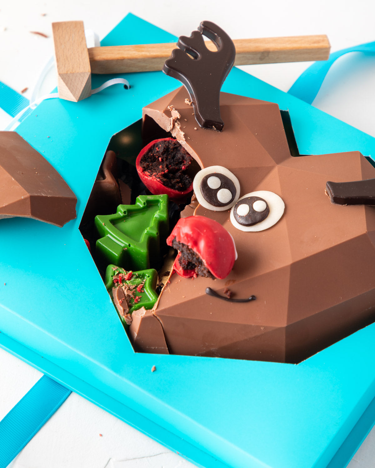 Piñata Reindeer by NJDChocolate & ConfectioneryYour Gift Contains: • Reindeer face Piñata made with approx. 400gms Milk Chocolate • 1 large Brownie cake pop as the nose • Filled with 10 pieces Christmas theme Milk chocolate Box Size: LxBxH: 21x25x9.5cm HA