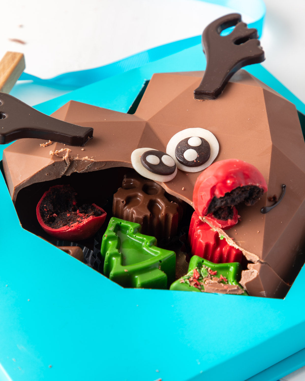 Piñata Reindeer by NJDChocolate & ConfectioneryYour Gift Contains: • Reindeer face Piñata made with approx. 400gms Milk Chocolate • 1 large Brownie cake pop as the nose • Filled with 10 pieces Christmas theme Milk chocolate Box Size: LxBxH: 21x25x9.5cm HA