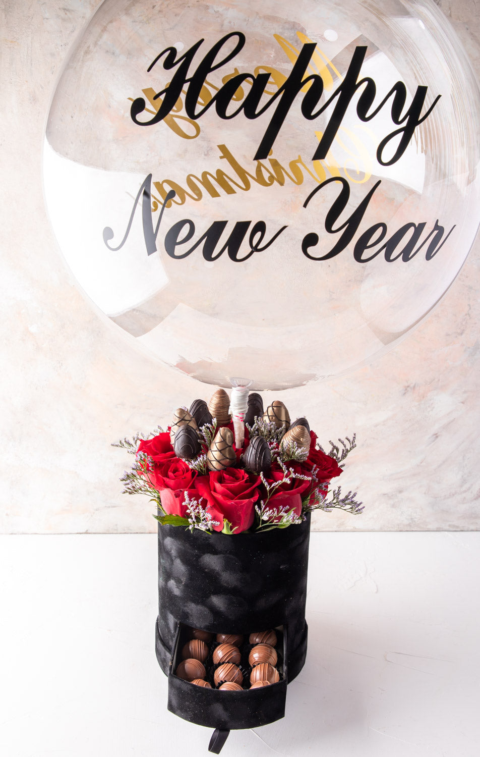 Christmas and New Year Combo by NJDFlowersYour Gift Contains: • 1 Large Balloon with Merry Christmas / Happy New Year message • 11 Red roses • 10 pieces chocolate covered strawberries • 16 pieces Milk chocolate truffles Box Size: LxBxH: 17X17X64CM HANDLIN