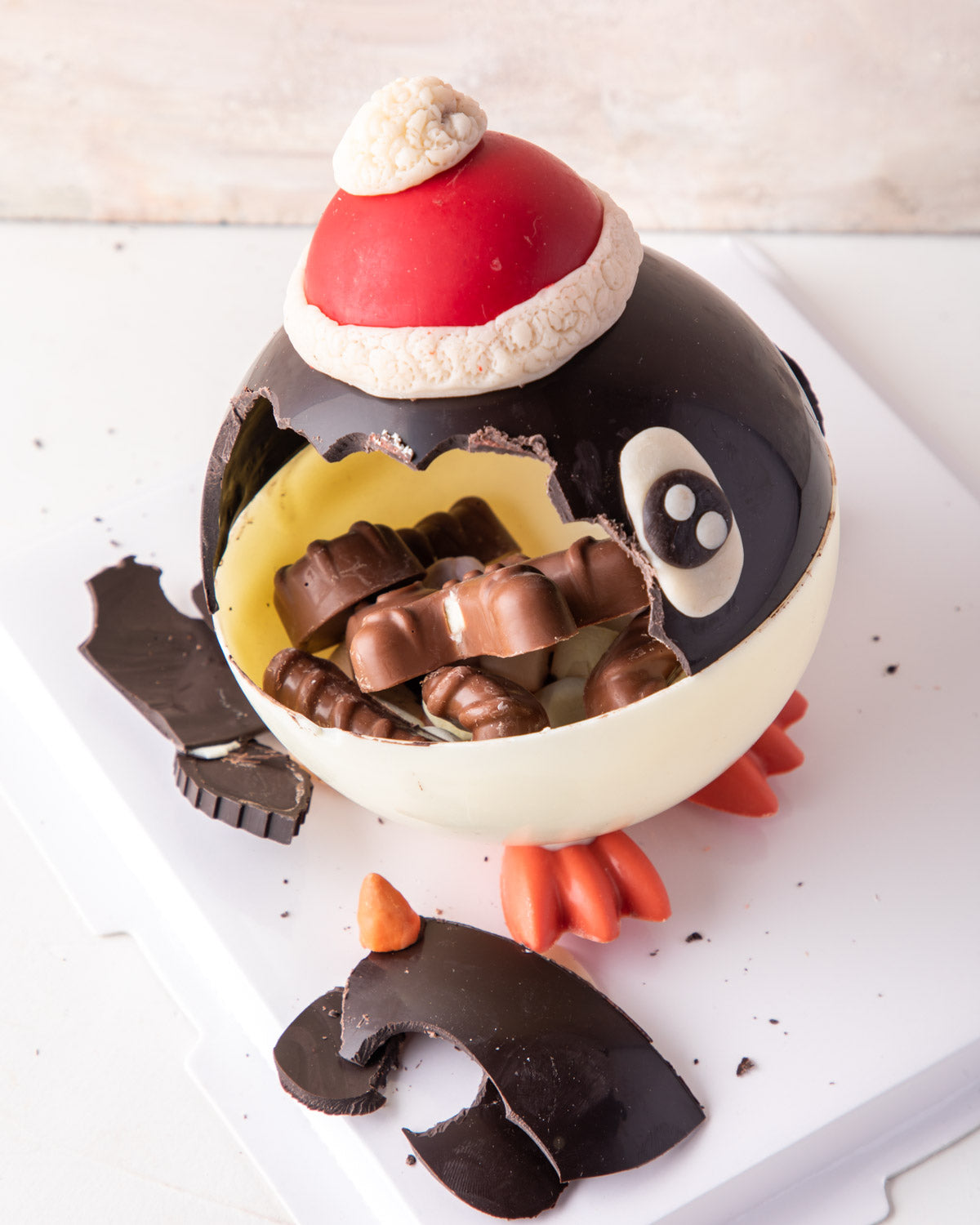 Piñata Penguin by NJDChocolate & ConfectioneryYour Gift Contains: • 300gms Dark and White chocolate Piñata Penguin • Filled with 10 pieces Christmas theme milk chocolate Box Size: LxBxH: 23.5X23.5X18cm HANDLING AND STORAGE Keep away from direct heat and s