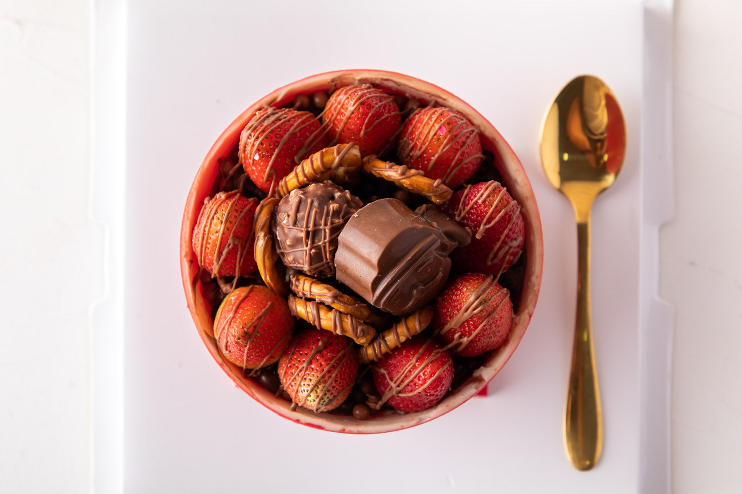 Season's Special Indulgence by NJDChocolate & ConfectioneryYour Gift Contains: • Edible chocolate bowl with Hazelnut praline • 12 fresh strawberries • Pretzels • 3 Rocher • 1 Spoon • Total weight: 750gms (20gms +/-) Box Size: LxBxH: 23x23x18cm HANDLING AN