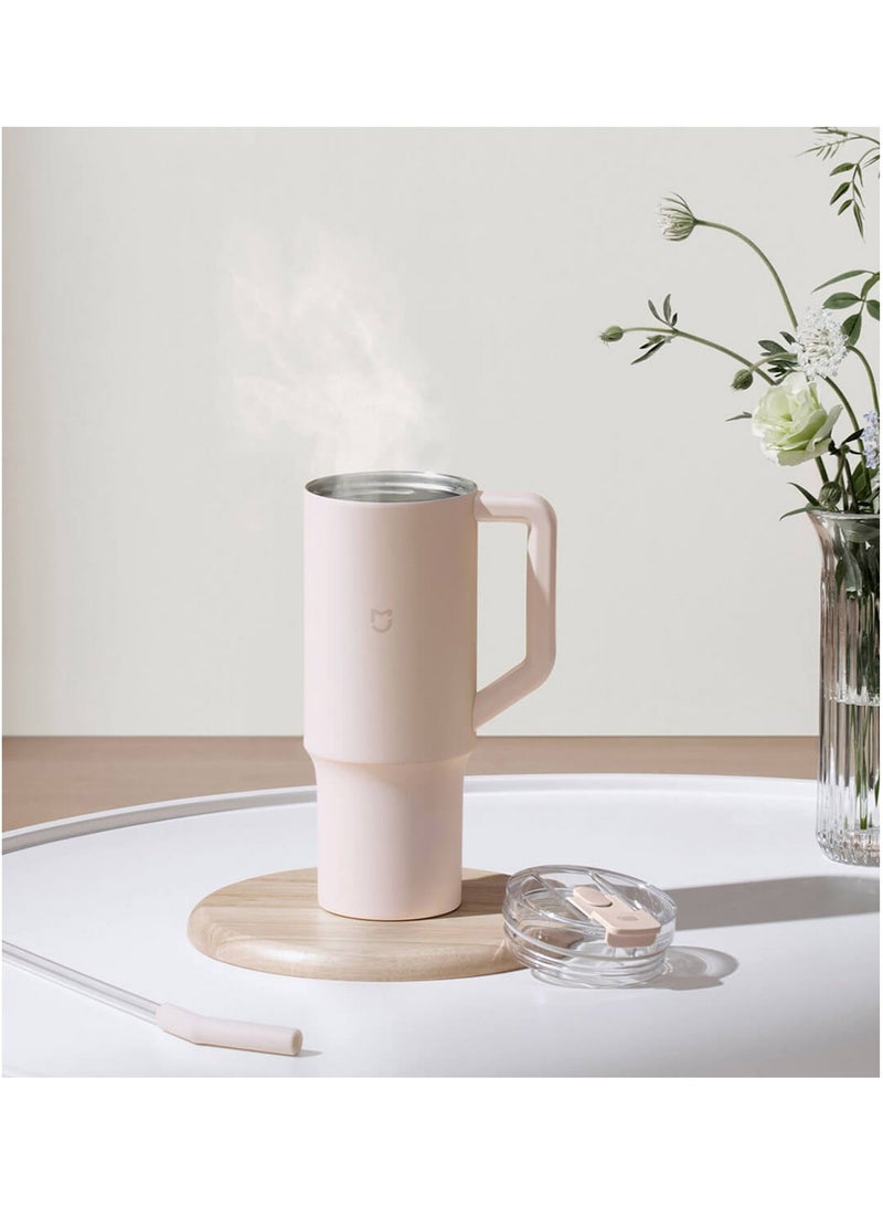 Pink mug with a wooden coaster on a white surface with a light background