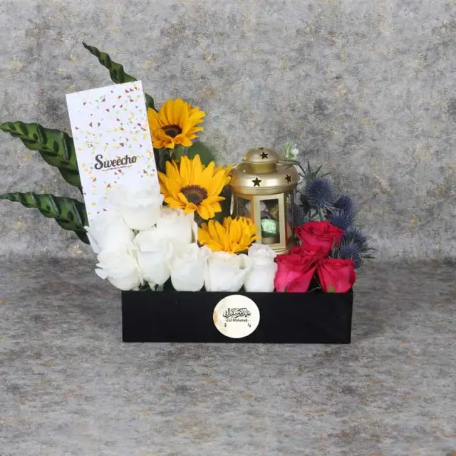 Eid Floral Hamper BlackGifts and HampersHamper Includes: Premium Chocolates By Sweecho 100gm Chocolate Coated Dates with Nuts 8 pcs in Lantern 3 Sunflowers 8 White Roses 7 Dark Pink Roses 2 Stems Blue Eryngium Leaves and Fillers- 4 Stems Cordyline Leaves