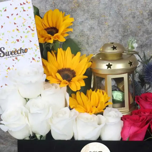 Eid Floral Hamper BlackGifts and HampersHamper Includes: Premium Chocolates By Sweecho 100gm Chocolate Coated Dates with Nuts 8 pcs in Lantern 3 Sunflowers 8 White Roses 7 Dark Pink Roses 2 Stems Blue Eryngium Leaves and Fillers- 4 Stems Cordyline Leaves