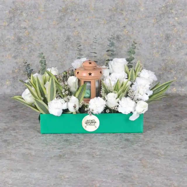 Eid Floral Hamper GreenGifts and HampersHamper Includes: Premium Chocolates By Sweecho 100gm in Lantern 9 White Carnations 10 White Roses Fillers - 3 Stems White Wax and 3 Stems Song of India Ramadan Kareem Topper Prepared in a Green Acrylic Tray