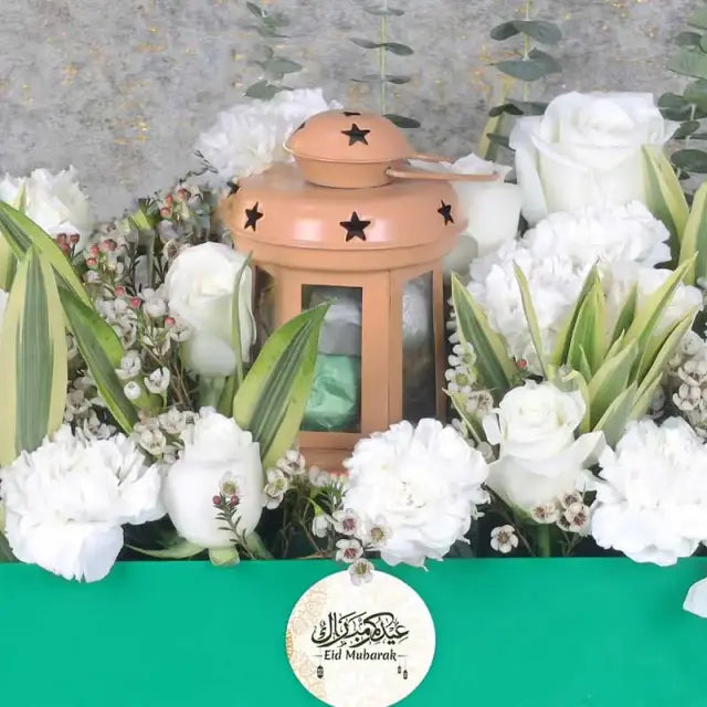 Eid Floral Hamper GreenGifts and HampersHamper Includes: Premium Chocolates By Sweecho 100gm in Lantern 9 White Carnations 10 White Roses Fillers - 3 Stems White Wax and 3 Stems Song of India Ramadan Kareem Topper Prepared in a Green Acrylic Tray