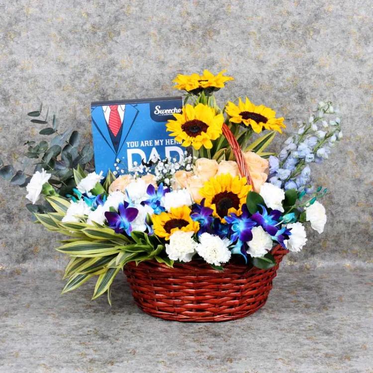 May Hero Flowers Basket and ChocolatesChocolate & ConfectioneryPremium Assorted Chocolates 16 Pcs By Sweecho, 5 Sunflowers, 2 Blue Delphinium, 4 Blue Orchid, 8 Peach Roses, 14 White Carnations, Leaves : 3 Song of India and 3 Eucalyptus, Fillers : 1 Gypso,