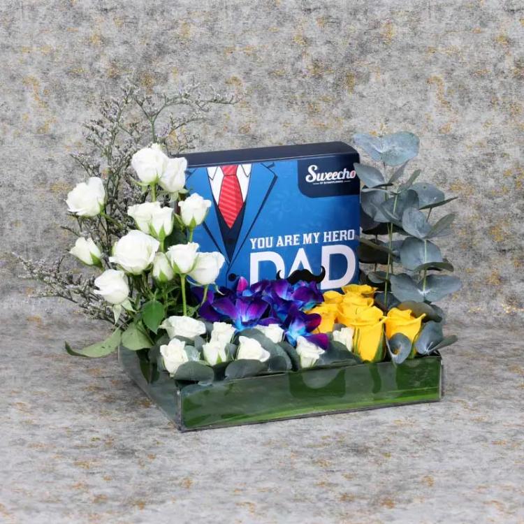 Hero Dad Flowers and Chocolate ArrangementChocolate & ConfectioneryPremium Assorted Chocolates 16 Pcs By Sweecho, 2 Blue Orchids, 6 Yellow Roses, 3 Stems White Baby Roses, Leaves : 5 Eucalyptus, Fillers : 1 Limonium, Prepare in Acrylic Tray - 33x27cm.
