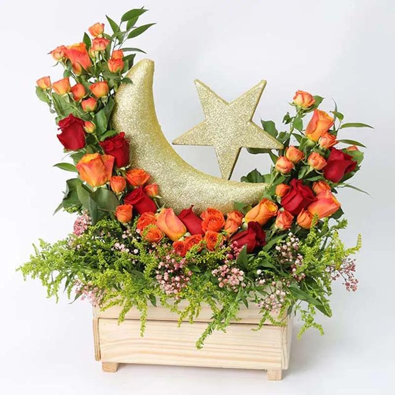 Auspicious Floral Wishes OrangeFlowersProduct Description 7 Red Roses 6 Orange Roses 6 Stems Orange Baby Roses 5 Stems Solidago Leaves and Fillers - 2 Italian Ruscus, Red Sprayed Gypso and 5 Single Ruscus Golden Crescent Moon and Star Prepared in a Wooden