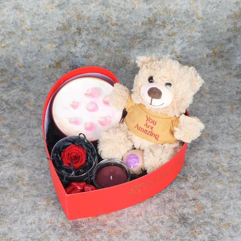 Womens Day Gift Box RedGifts and HampersGift Includes: 1 Red Forever Rose in Black Box Premium Rose Flavor Milk Cake 500gm You Are Amazing Teddy Bear 20gm 1 Jar Candle 1 Bath Bomb Arranged in a Heart Shape Box