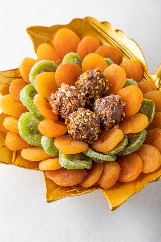 The Golden leaf by NJDNuts, Dates & Dried FruitsYOUR GIFT CONTAINS Content: Dried Kiwis 150gms Dried Apricot 500gms Assorted Truffles - 4pcs Flavors: Assorted truffles with Praline, Ganache and caramel fillings Tray dimensions: Wide: 25cm Height: 26.5cm H